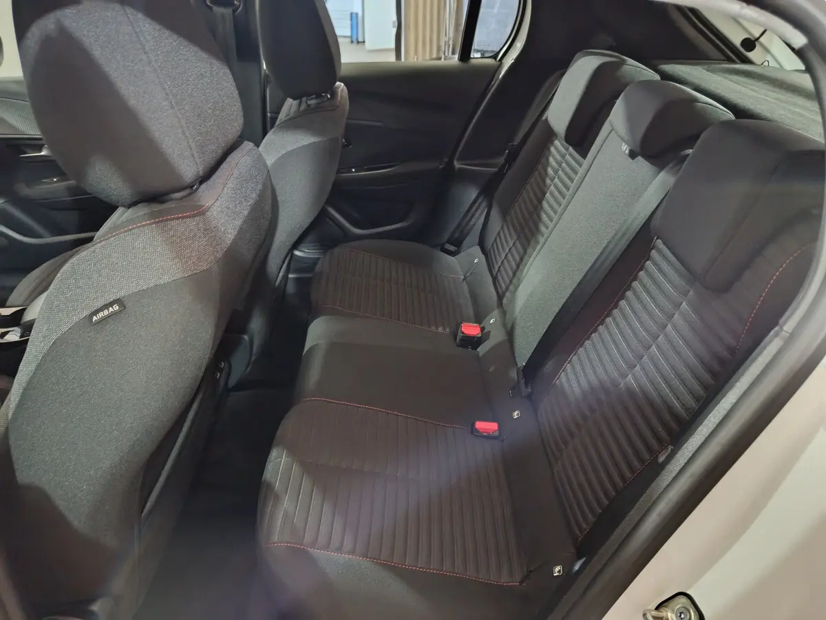 Banquette arrière noire avec surpiqûres rouges vue côté droit dans une Peugeot 208 électrique blanche 2023.