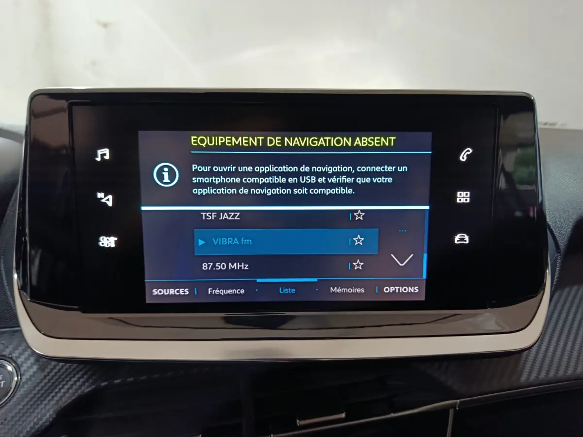 Écran tactile central de 7 pouces du tableau de bord de la Peugeot 208 électrique blanche, affichant les options radio.