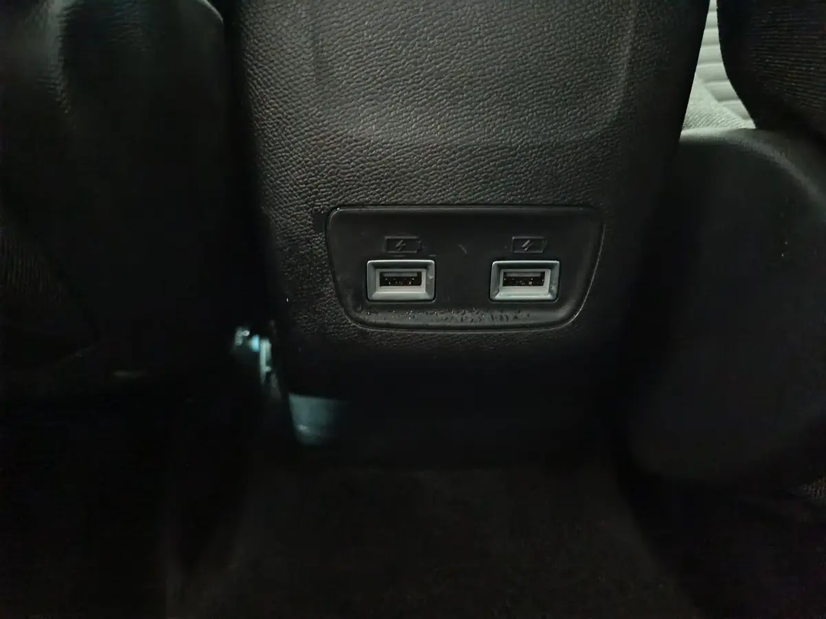 Prise double USB arrière sur console centrale noire dans l'habitacle de la Peugeot 208 électrique blanche 2023.