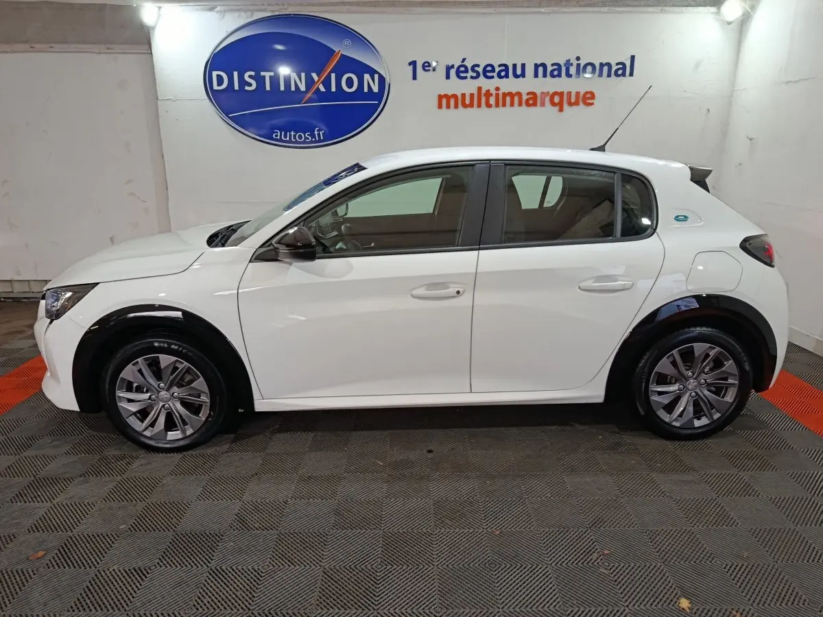 Peugeot 208 électrique blanc vue de profil côté gauche, avec jantes alliage et logo e-208 sur l'aile arrière.