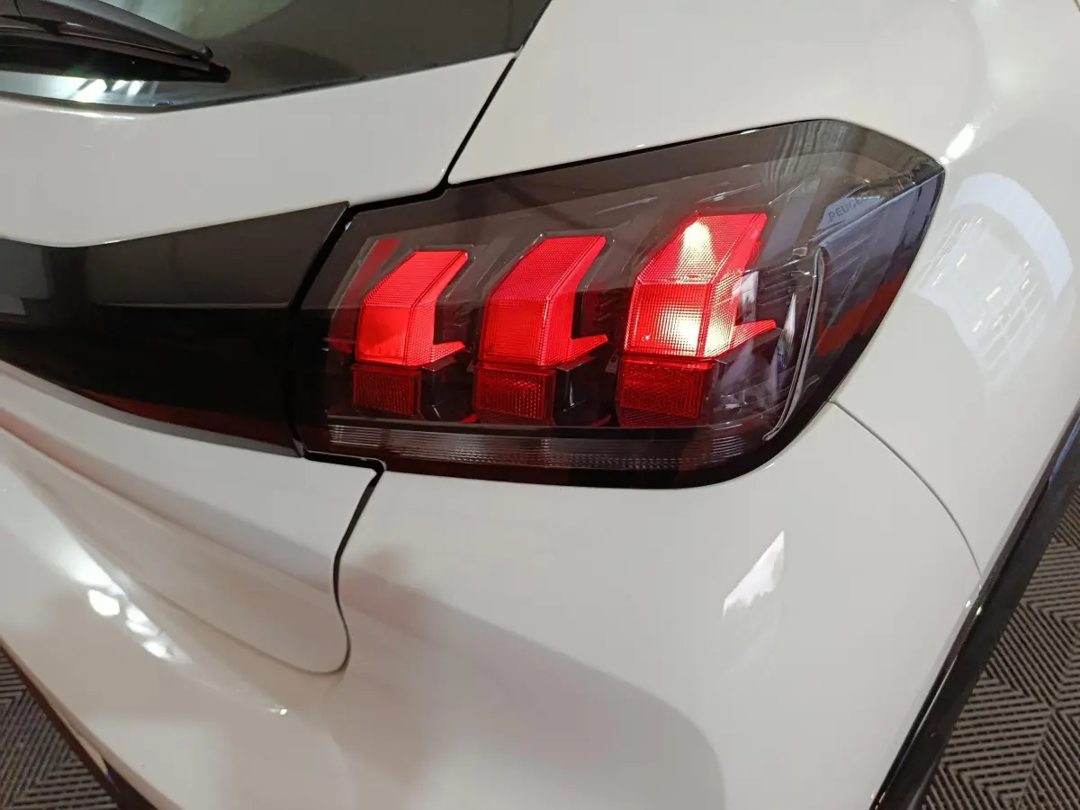 Gros plan sur le feu arrière droit rouge d'une Peugeot 208 électrique blanche, version 2023 Active Pack.