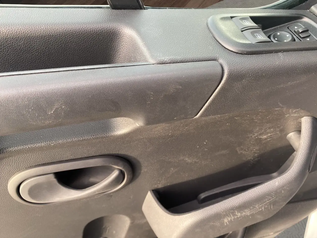 Gros plan sur la porte intérieure côté conducteur du Renault Master 2024 blanc, avec commandes de vitres et poignée noire.