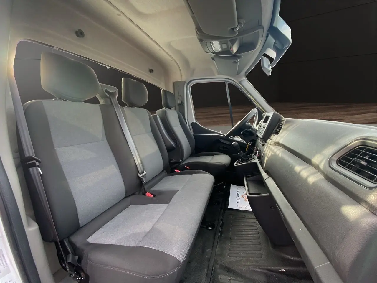Vue intérieure côté passager du Renault Master 2024, montrant les sièges tissu gris et tableau de bord noir.