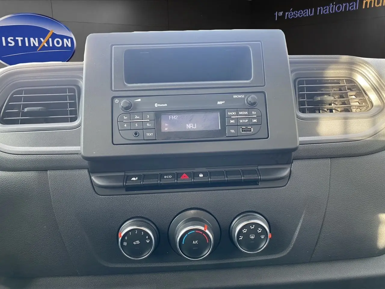 Vue rapprochée du tableau de bord noir du Renault Master 2024, avec commandes de climatisation et radio affichant NRJ.