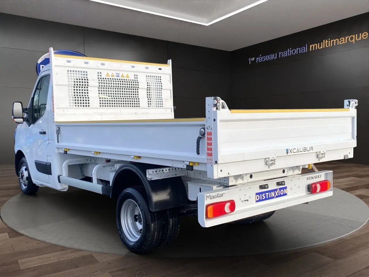 Vue 3/4 arrière droite d’un Renault Master blanc version benne, avec ridelles métalliques et cabine simple.