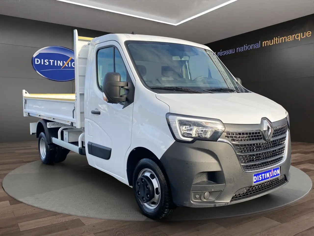 Renault Master blanc en 3/4 avant droit, benne arrière visible, calandre noire et phares LED distinctifs.