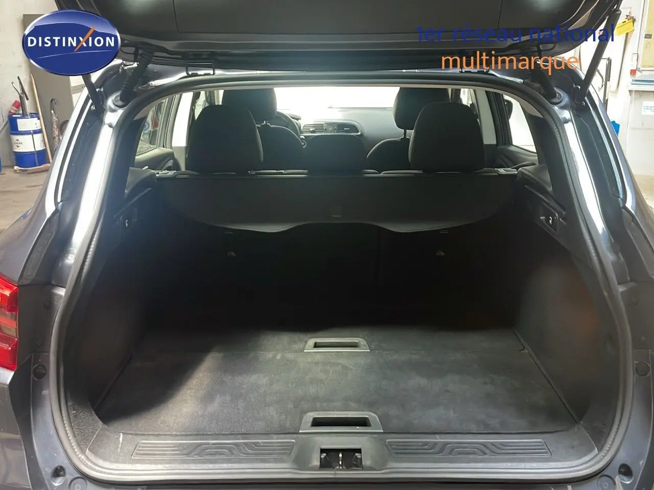 Coffre ouvert d'un Renault Kadjar bleu foncé métal vu de l'arrière, montrant l'espace de chargement vide et les sièges arrière.