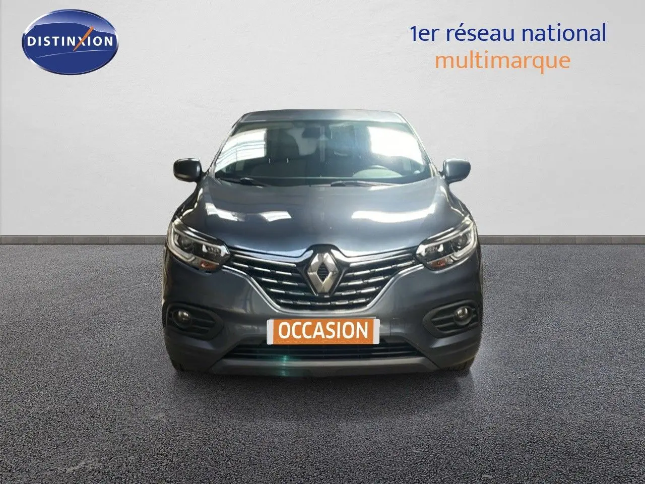 Renault Kadjar bleu foncé métal vu de face, avec calandre chromée et phares LED allumés.