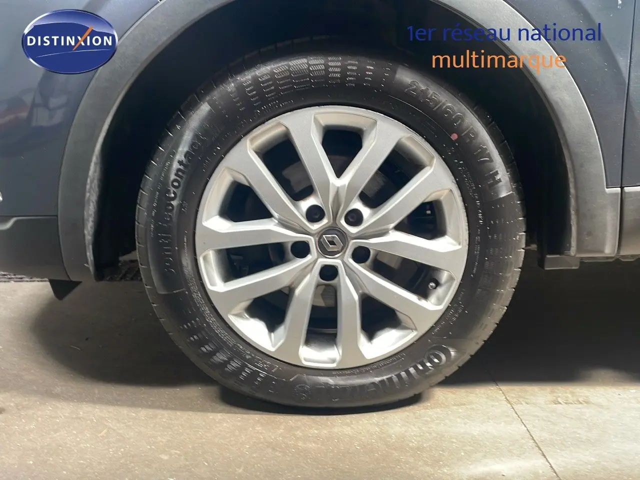 Gros plan sur la roue avant gauche d'un Renault Kadjar bleu foncé métal avec jante alliage distinctive.