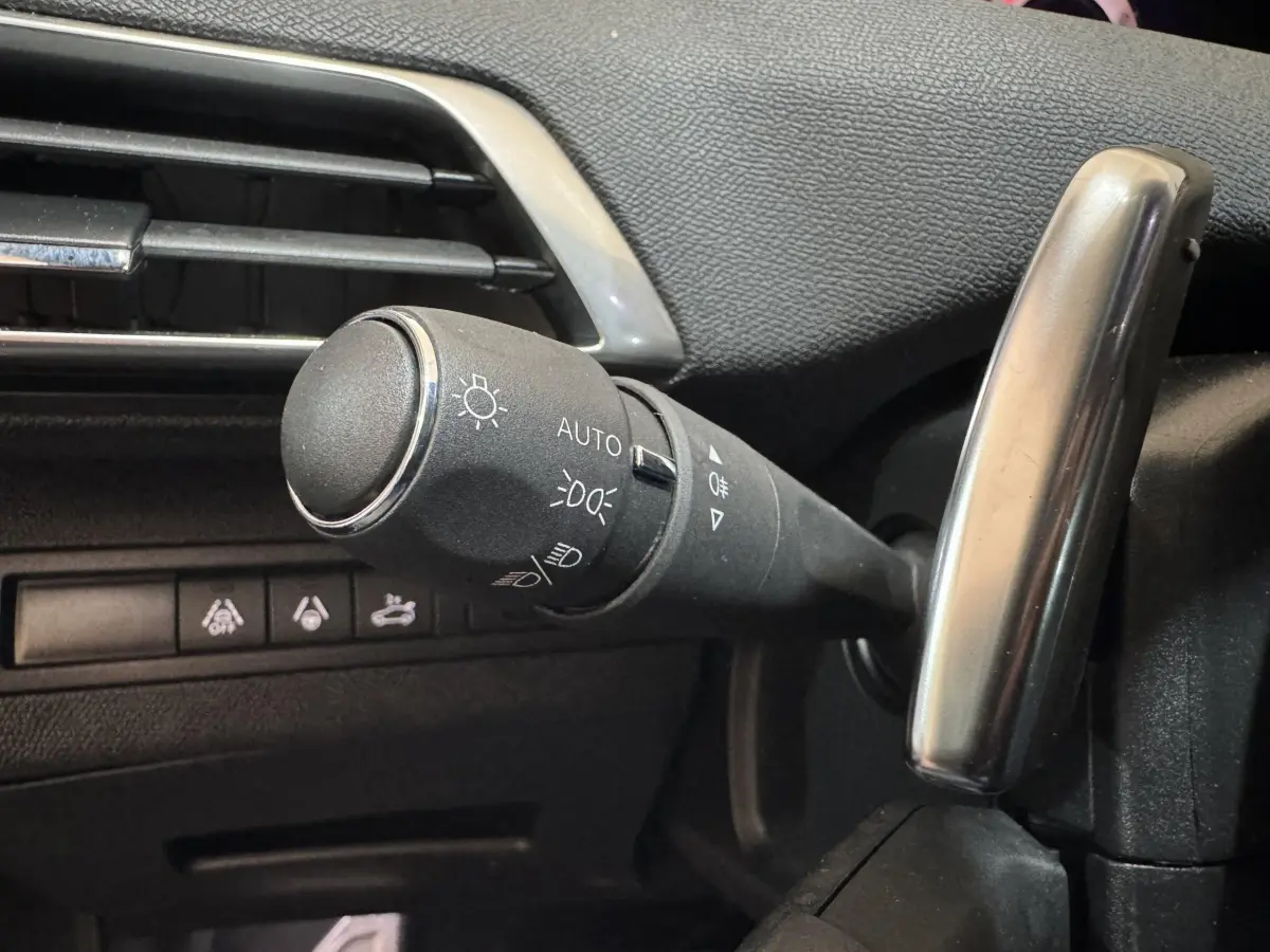 Gros plan sur la commande des phares et clignotants côté gauche du tableau de bord noir du Peugeot 3008 gris clair.
