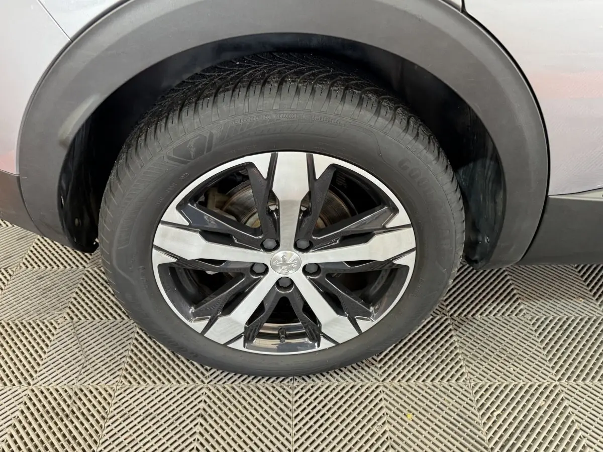 Gros plan sur la roue avant gauche d’un Peugeot 3008 gris clair, avec jante alliage bicolore noire et argentée.