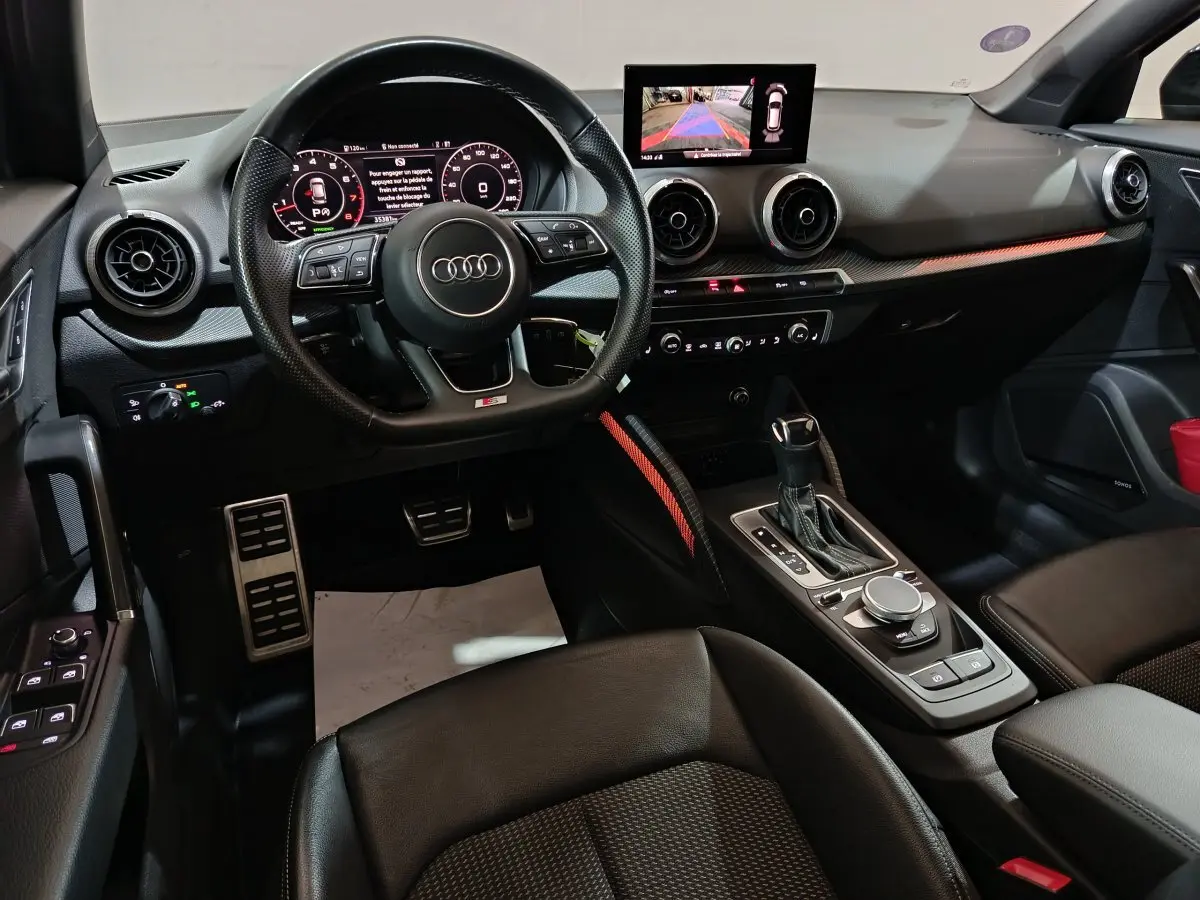 Intérieur noir de l'Audi Q2 35 TFSI 2022, vue côté conducteur sur volant, tableau de bord digital et console centrale.