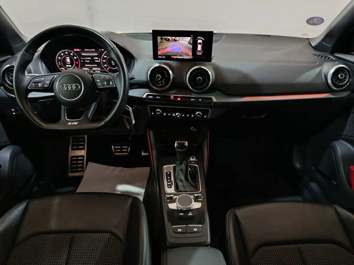 Vue intérieure de l'Audi Q2 35 TFSI S Line Plus 2022, tableau de bord noir avec écran central et volant multifonctions cuir.