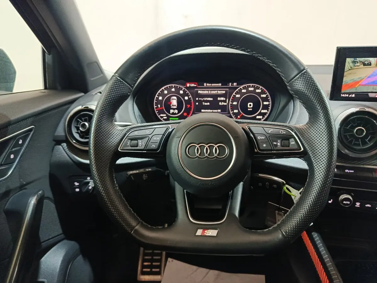 Vue frontale du volant cuir perforé avec logo Audi S Line, tableau de bord digital et écran de caméra de recul du Q2 noir 2022.