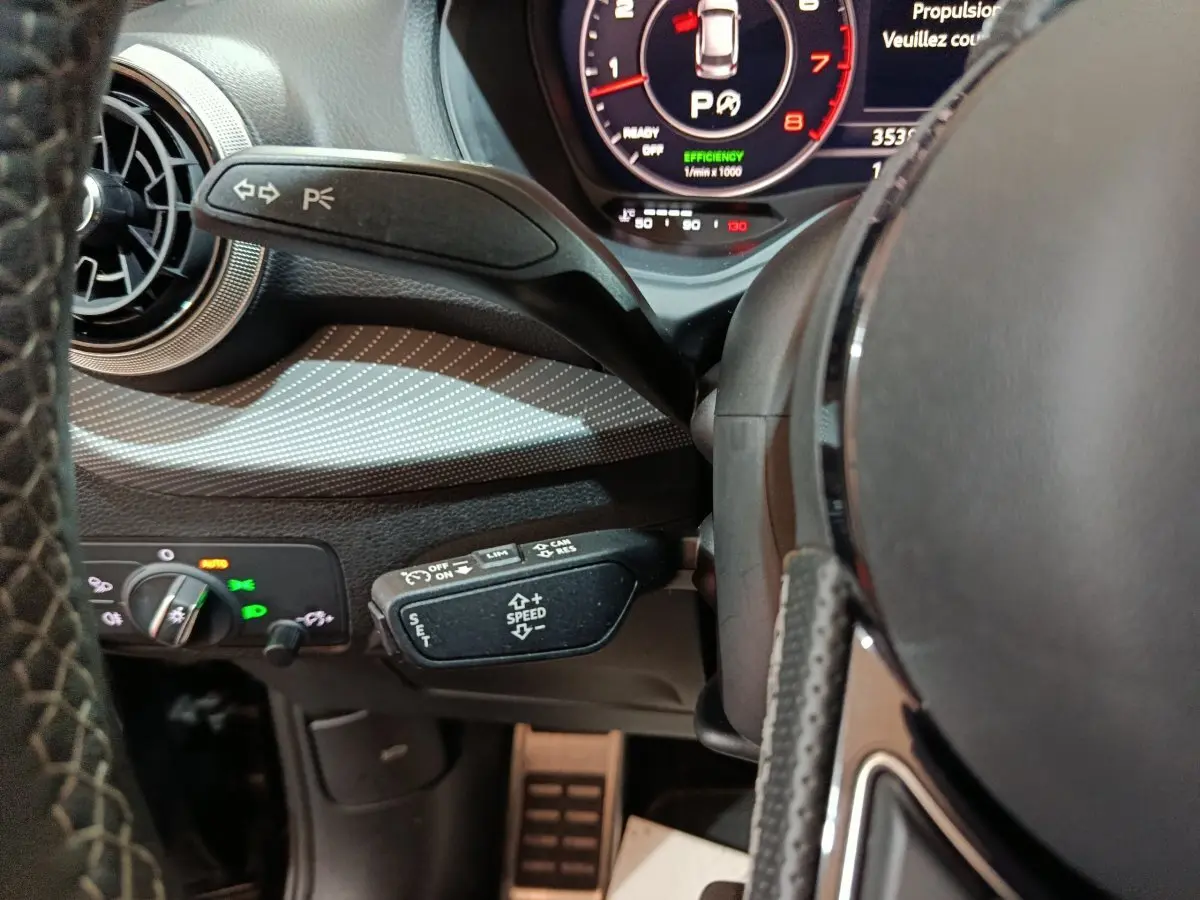 Gros plan sur le volant et commandes au volant de l'Audi Q2 35 TFSI noir, avec tableau de bord numérique visible.