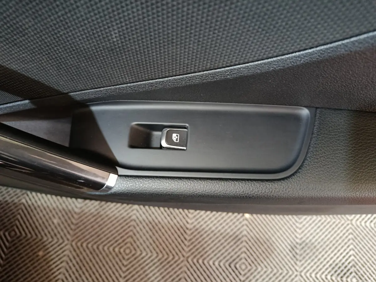 Gros plan sur le bouton de commande de vitre électrique côté gauche dans l'habitacle noir de l'Audi Q2 35 TFSI 2022.