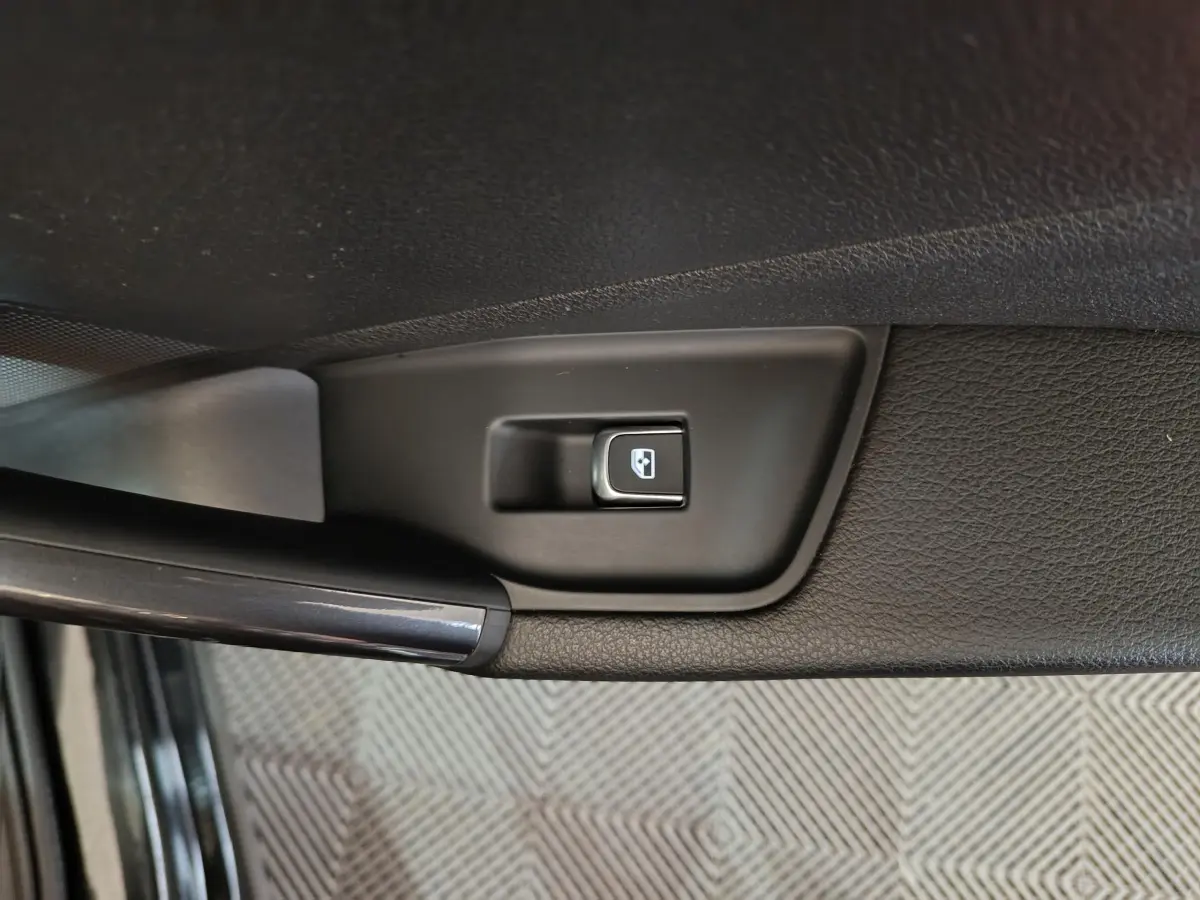 Bouton de commande de lève-vitre noir sur la portière intérieure côté gauche d'un Audi Q2 noir.