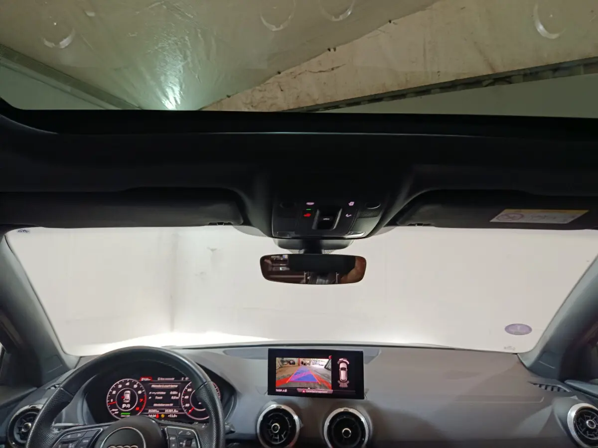 Vue intérieure avant de l'Audi Q2 noir 35 TFSI 2022 avec écran tactile et tableau de bord digital.