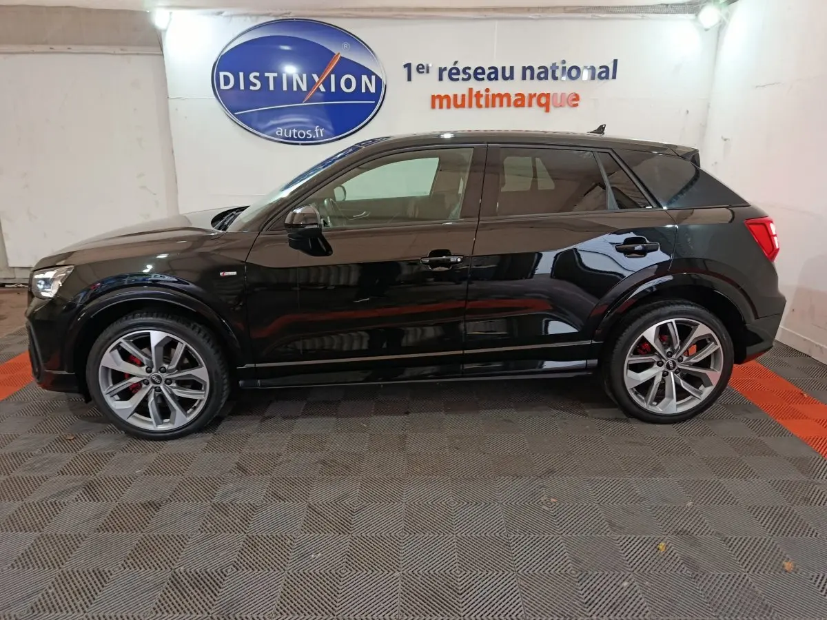 Profil côté gauche d'un Audi Q2 noir 35 TFSI S Line Plus 2022 avec jantes alliage et étriers rouges visibles.