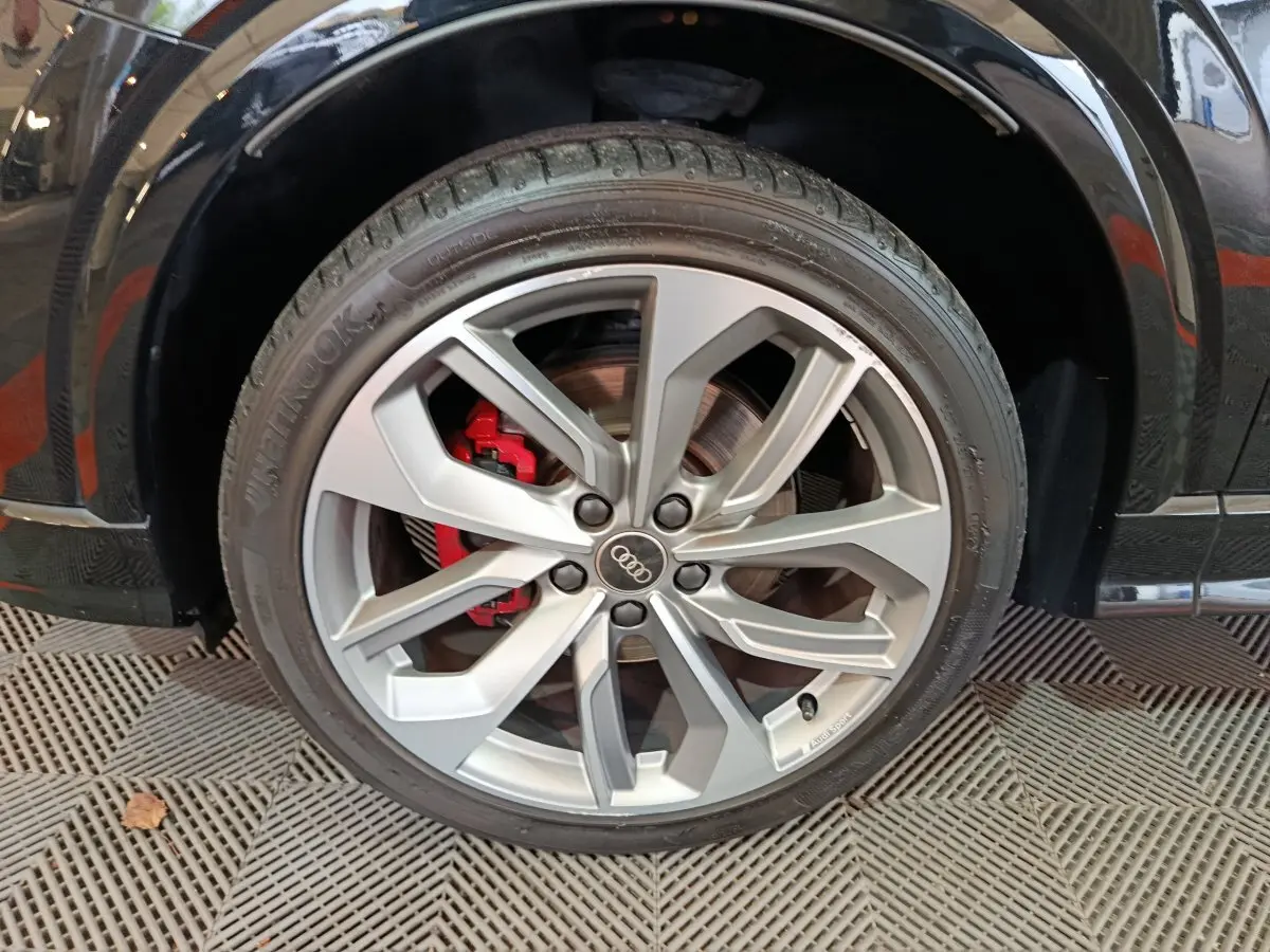 Gros plan sur la roue avant droite d’un Audi Q2 noir, jante alliage argent avec étrier de frein rouge visible.
