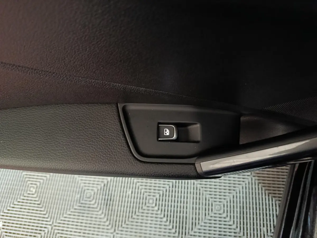 Bouton de verrouillage des portes sur la portière côté gauche d'un Audi Q2 noir 2022, finition S Line Plus.