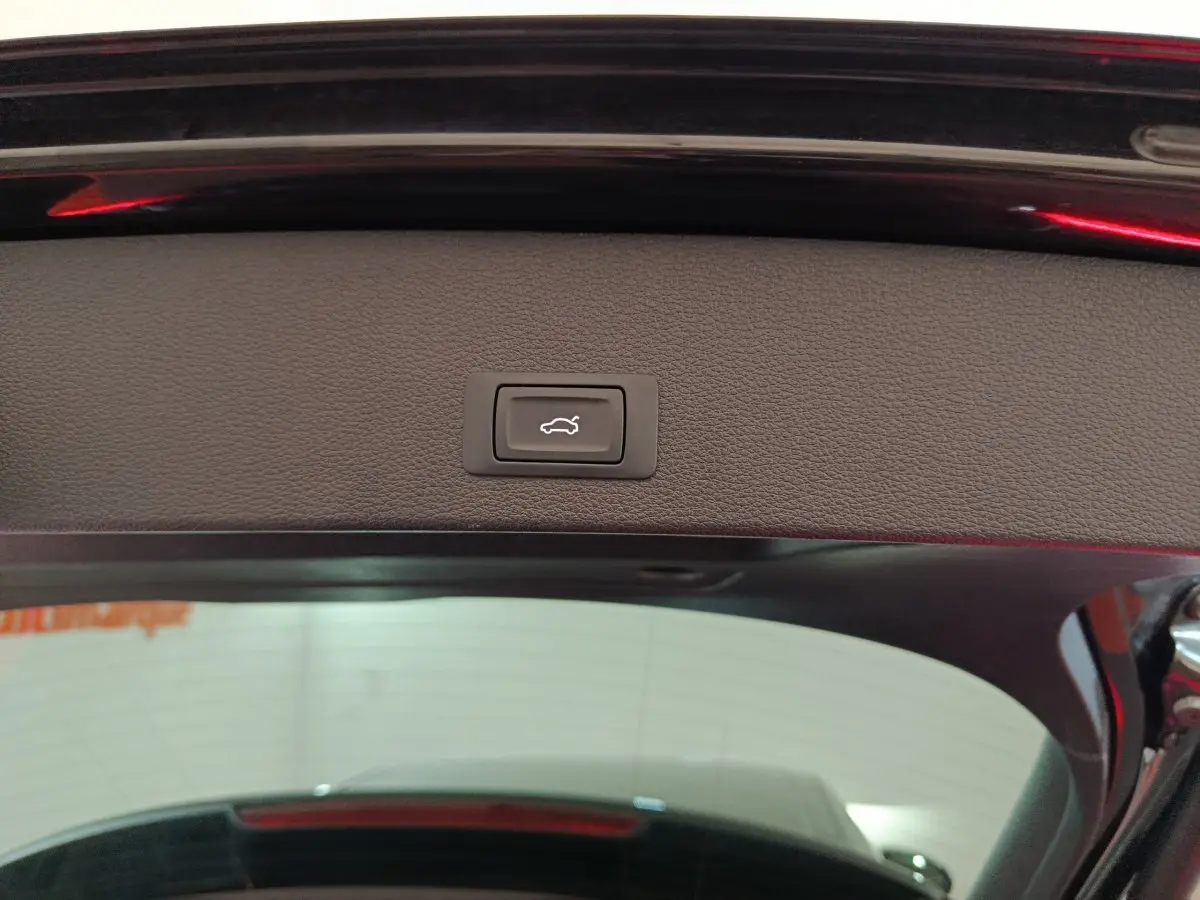 Bouton d'ouverture électrique du coffre sur le hayon intérieur d'un Audi Q2 noir, vue arrière rapprochée.