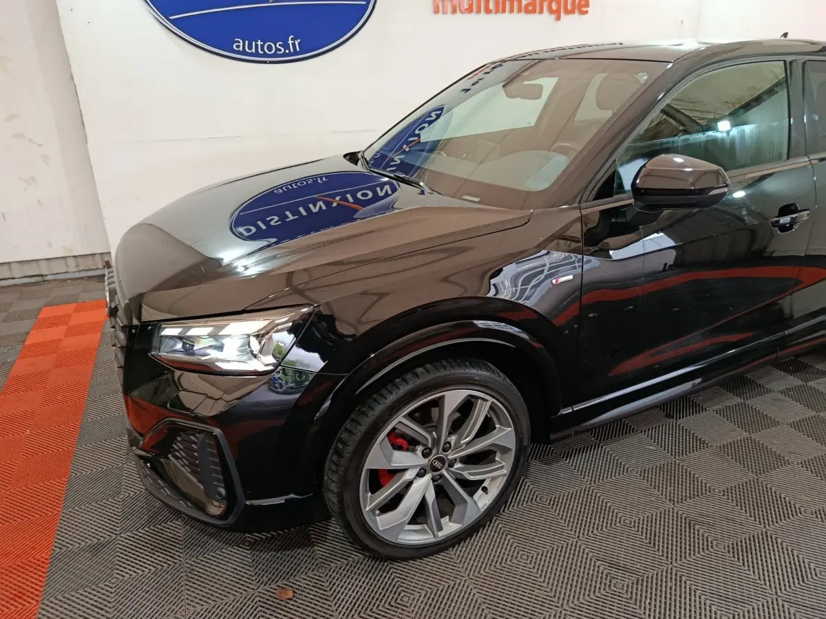 Audi Q2 35 TFSI S Line Plus noir vue 3/4 avant droit, avec jantes alliage et étriers de frein rouges visibles.