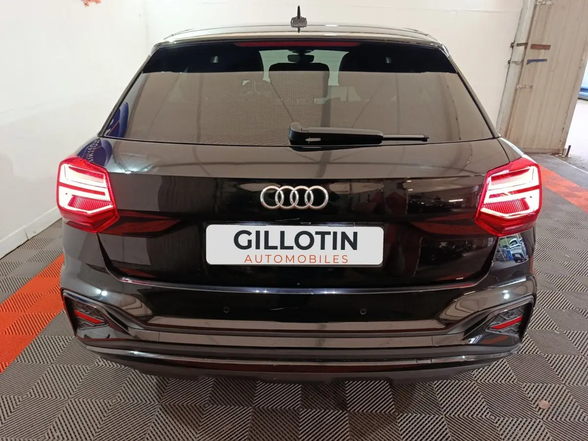 Vue arrière d'un Audi Q2 noir 2022 avec feux LED allumés et logo Audi bien visible sur le hayon.