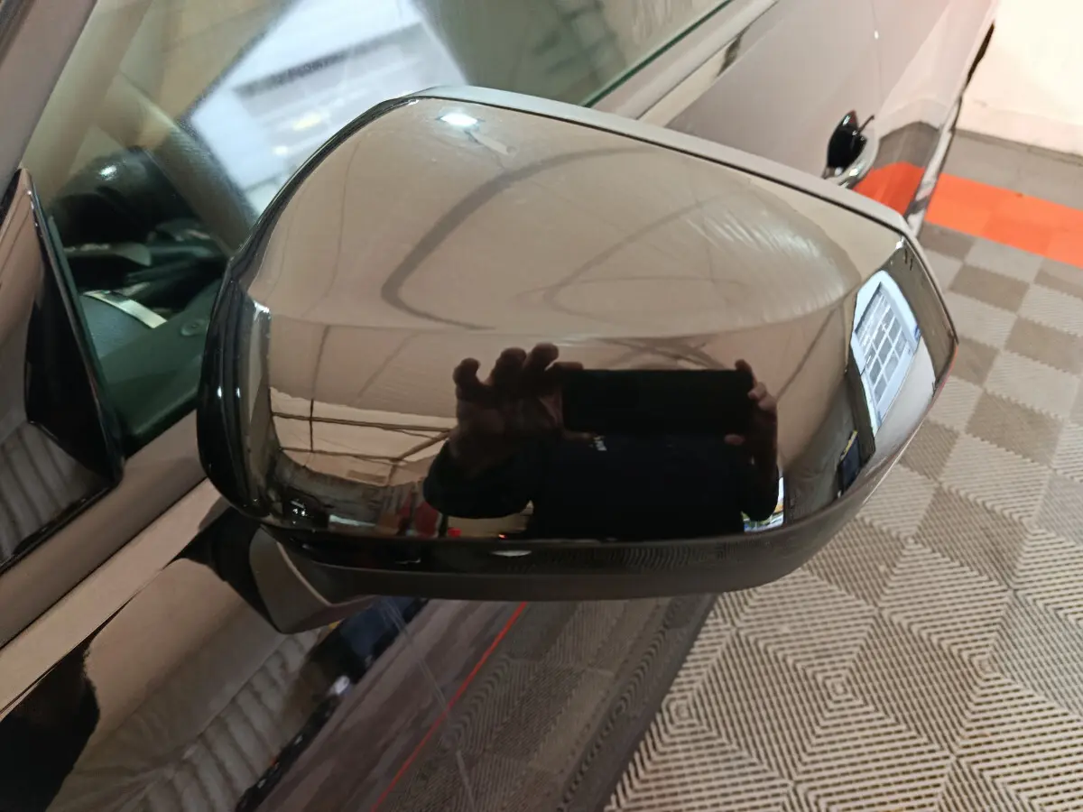 Rétroviseur extérieur noir brillant côté conducteur de l'Audi Q2 35 TFSI 2022 avec surface réfléchissante marquée.