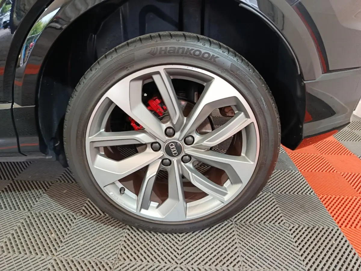 Gros plan sur la roue avant droite noire d’un Audi Q2 35 TFSI S Line Plus avec étrier de frein rouge visible.