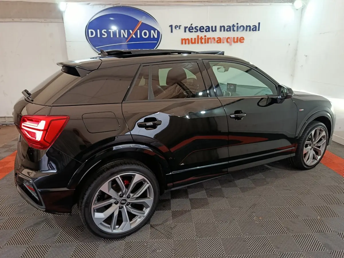 Audi Q2 35 TFSI S Line Plus noire vue de profil côté gauche avec jantes alliage et feux arrière allumés