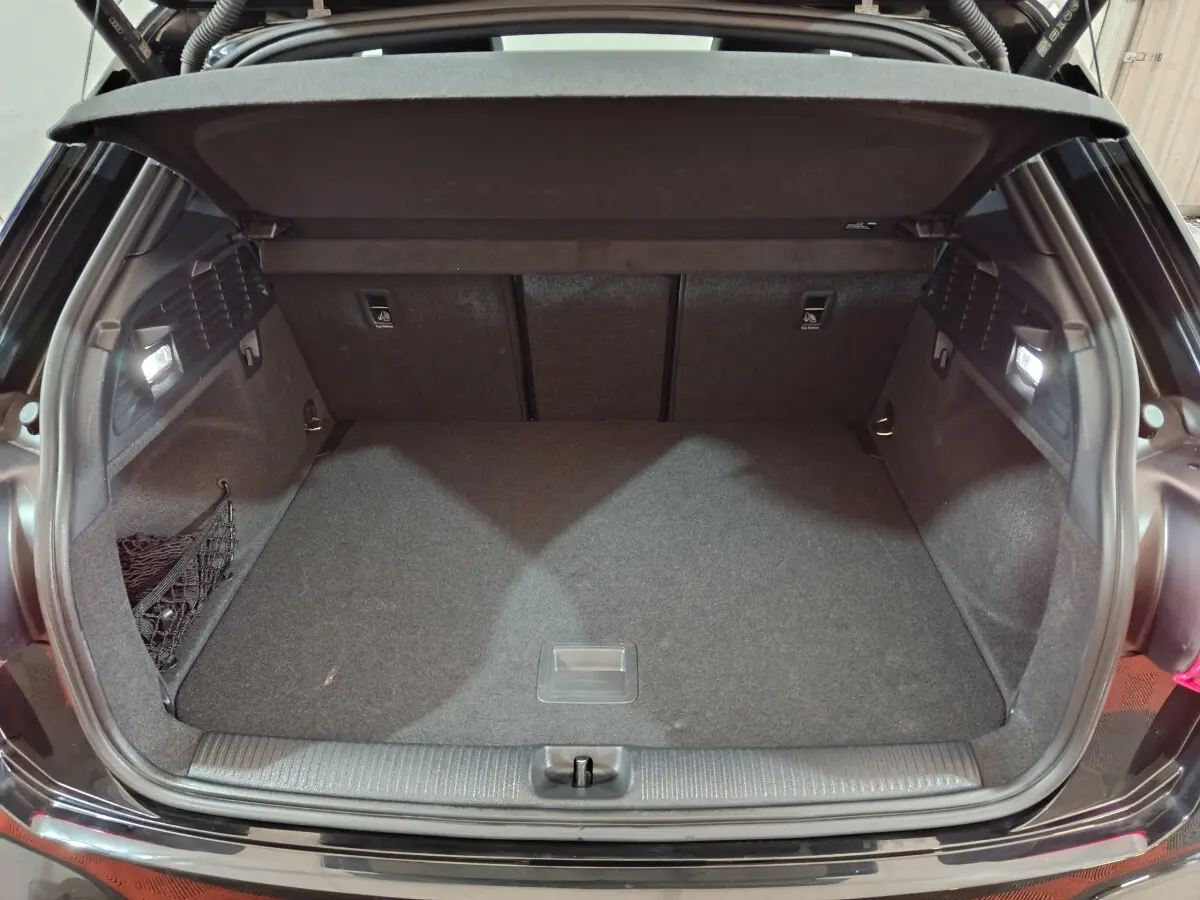 Coffre ouvert vu de l'arrière d'un Audi Q2 noir 2022, espace de chargement propre et éclairé.