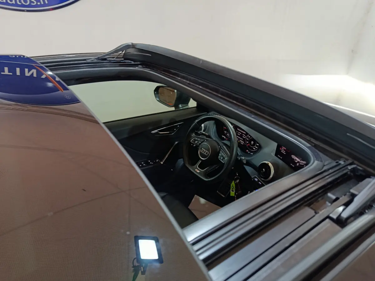 Vue intérieure côté conducteur d'un Audi Q2 noir 2022, volant cuir et tableau de bord numérique lumineux.