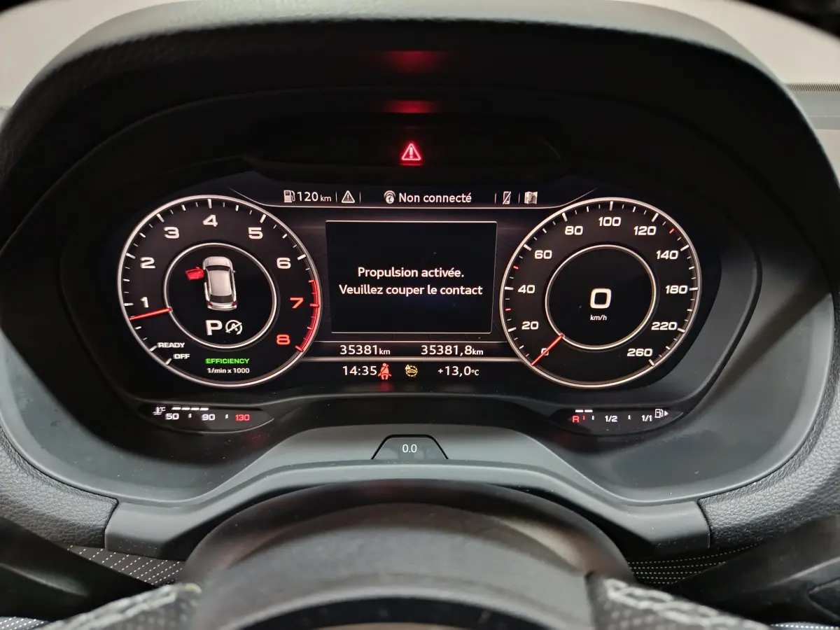 Vue rapprochée du tableau de bord numérique de l'Audi Q2 35 TFSI 150 S Line Plus avec affichage digital et message d'alerte.