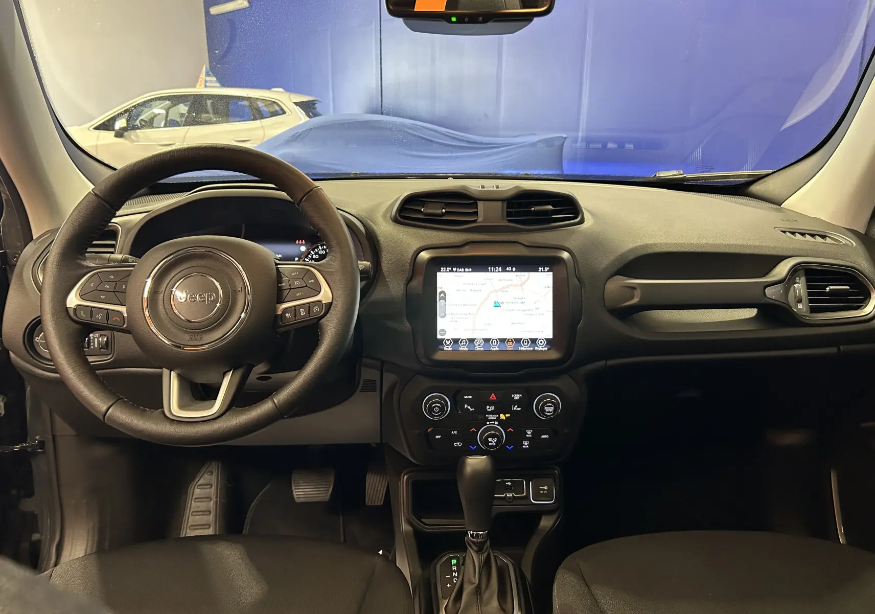 Vue intérieure frontale du tableau de bord du Jeep Renegade 2023 avec écran tactile et volant multifonctions en cuir.
