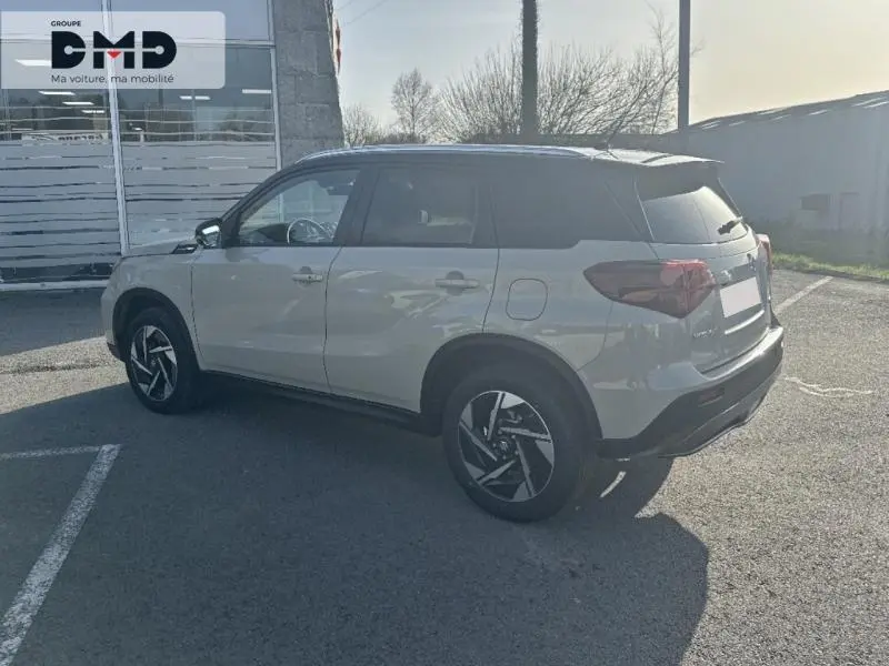 Suzuki Vitara 2026 hybride vue 3/4 arrière côté gauche, couleur ivoire Savanna avec toit noir et jantes alu noires.