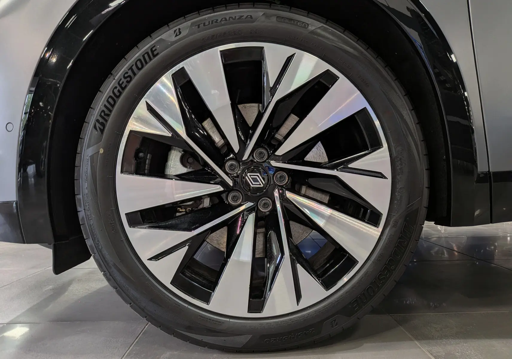 Gros plan sur la jante bi-ton noire et argentée d’un Renault Rafale gris schiste satin, avec pneu Bridgestone Turanza.