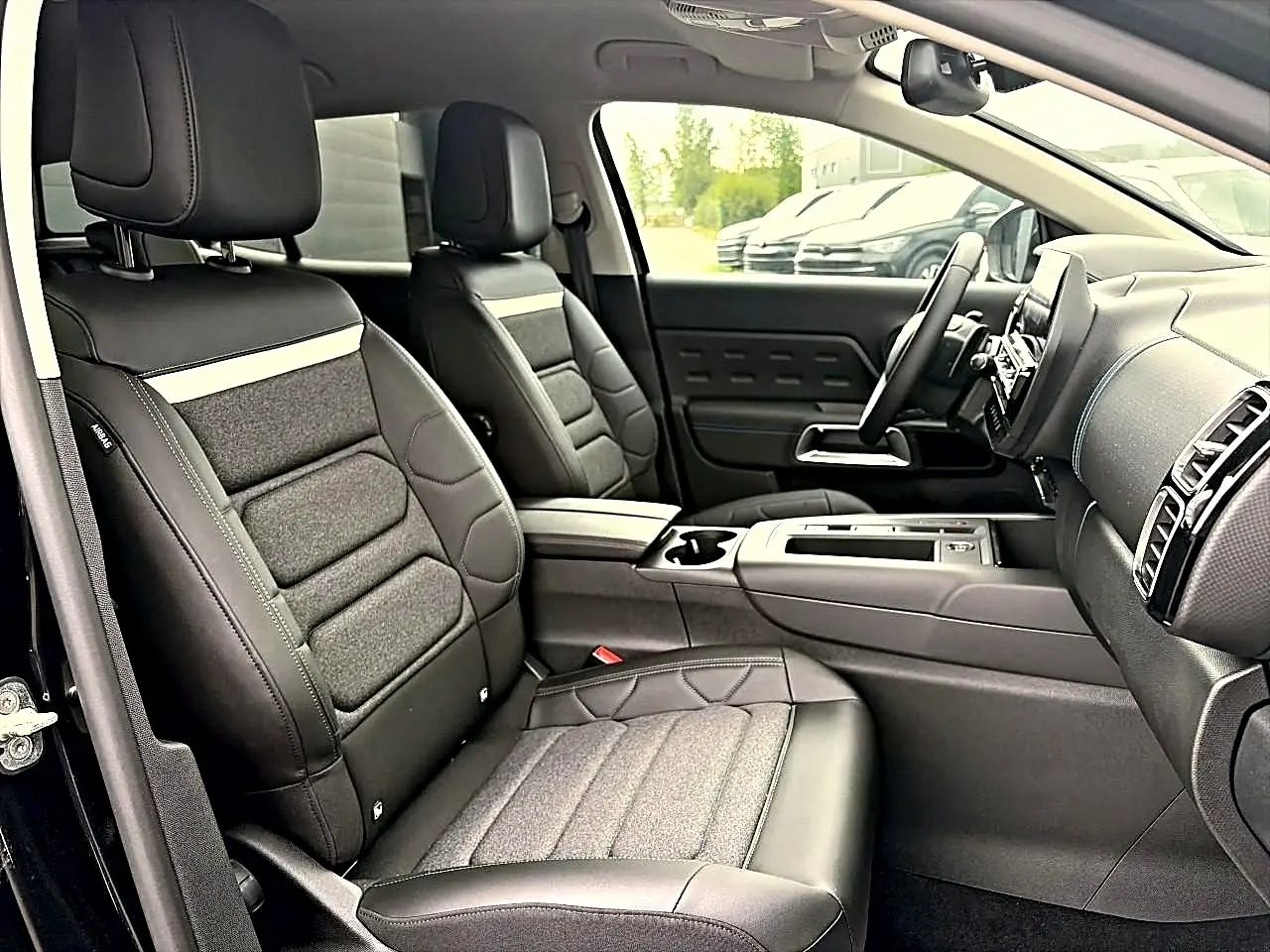 Vue intérieure côté conducteur du Citroën C5 Aircross 2025 noir, sièges cuir et tissu avec console centrale et tableau de bord moderne.