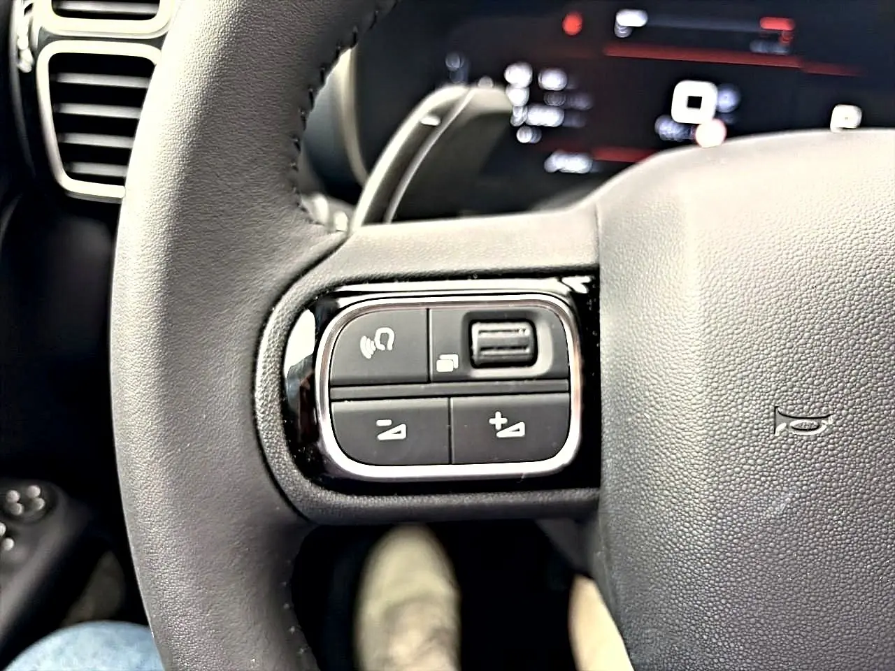 Gros plan sur les commandes gauche du volant cuir noir du Citroën C5 Aircross 2025, avec touches multifonctions.