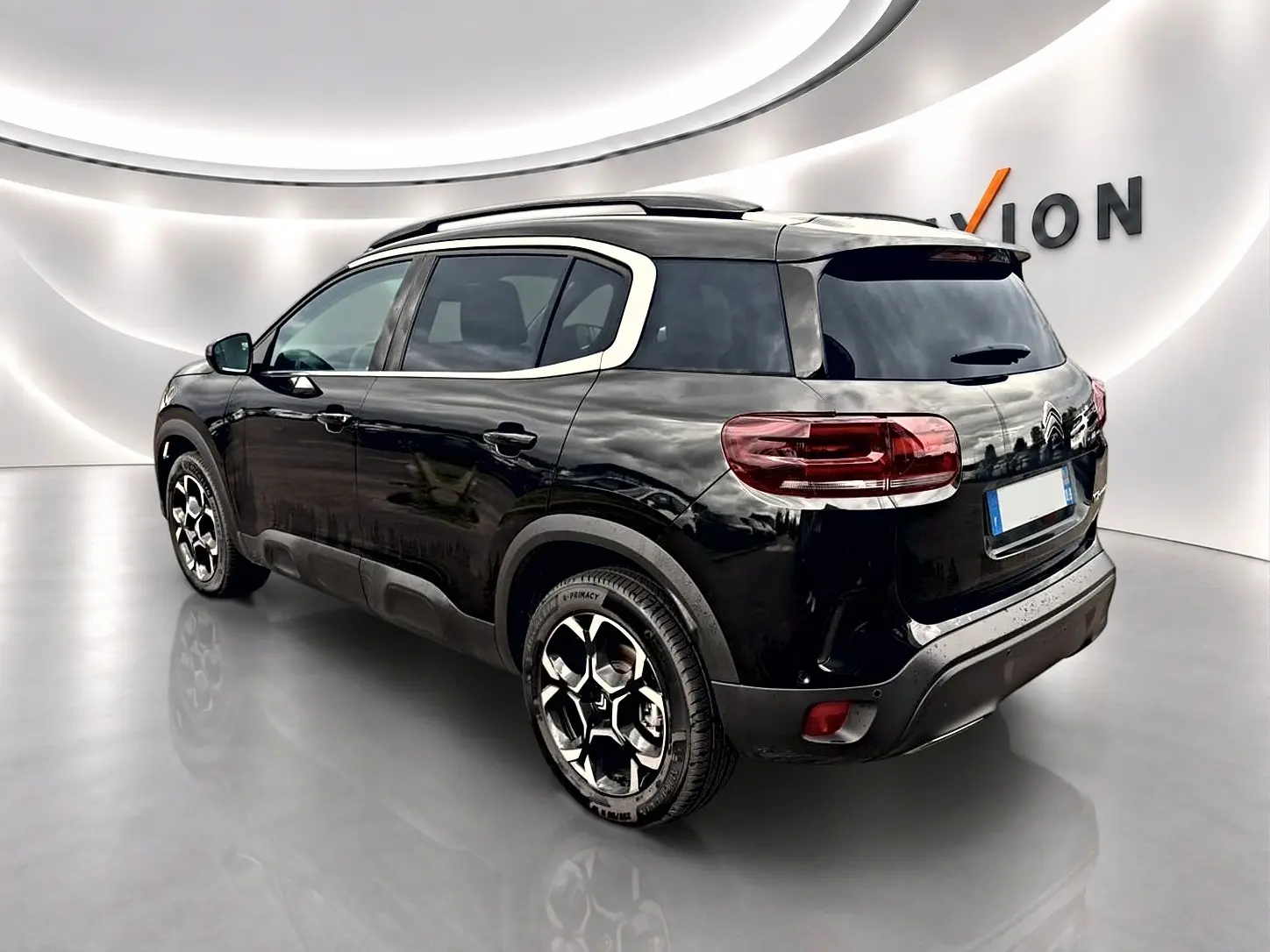 Citroën C5 Aircross noir vue 3/4 arrière droit, avec barres de toit et jantes alu distinctives.