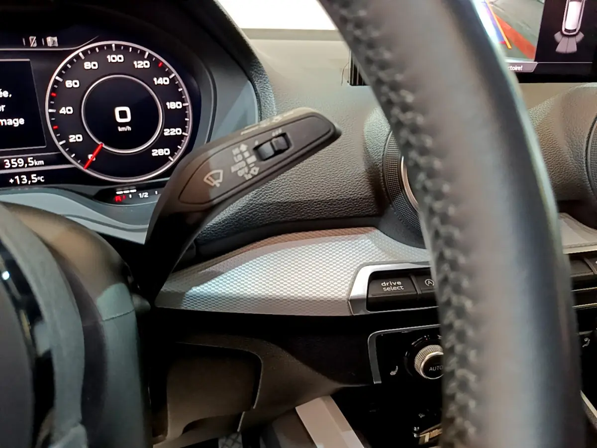 Vue rapprochée du tableau de bord et volant cuir de l'Audi Q2 gris clair, avec affichage numérique et commandes intégrées.