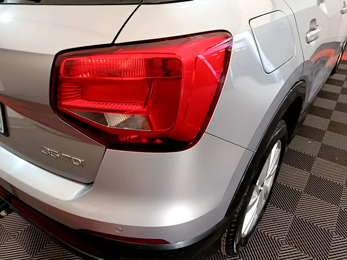 Vue arrière droite d'un Audi Q2 35 TDI gris clair avec feu arrière rouge et logo 35 TDI visible.