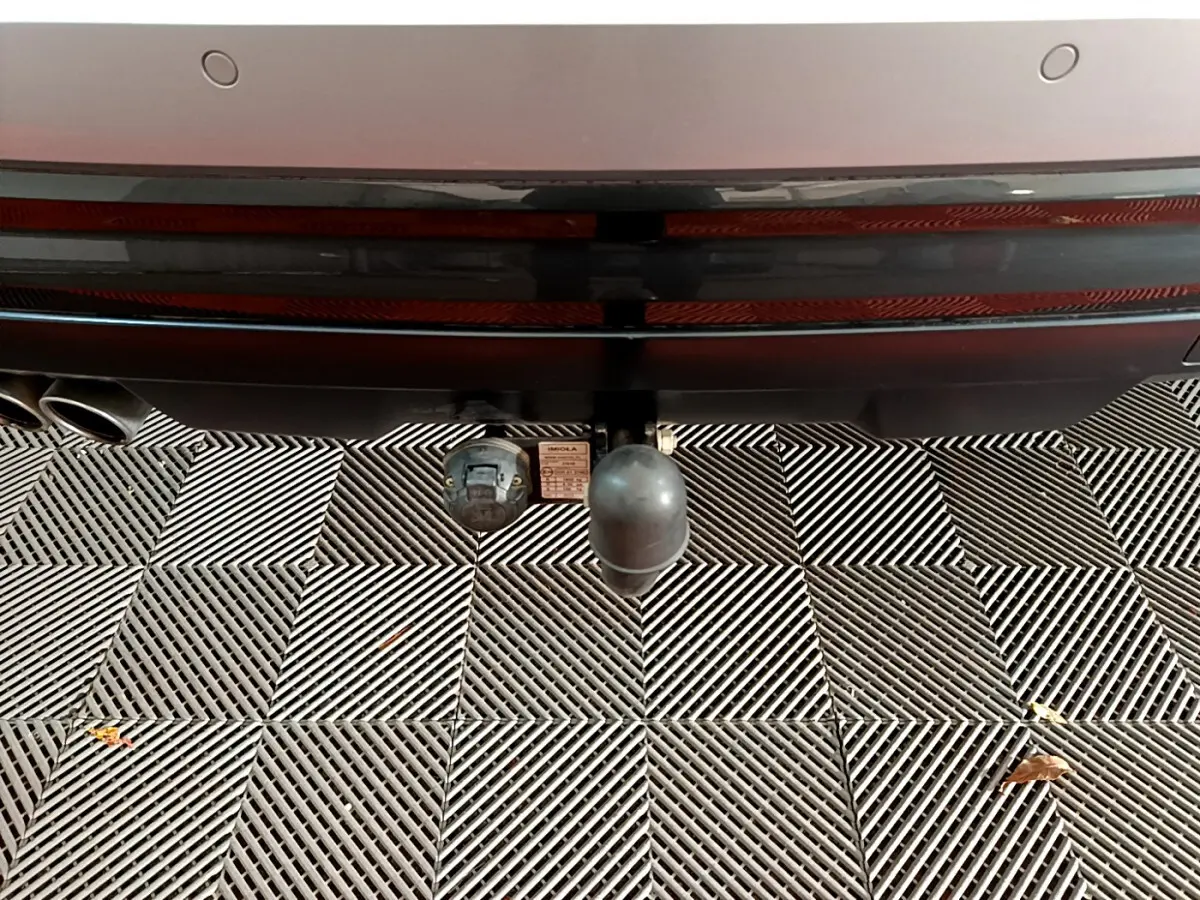 Gros plan sur l'attelage de remorque à l'arrière d'un Audi Q2 gris clair, avec double sortie d'échappement visible.