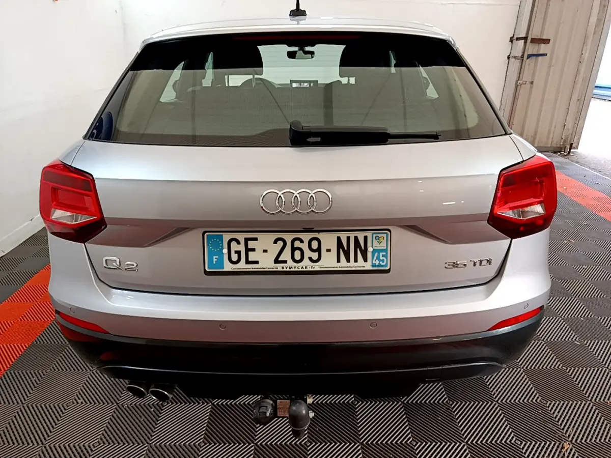 Vue arrière d'un Audi Q2 gris clair 35 TDI 150 Design avec double sortie d'échappement et attelage de remorque.
