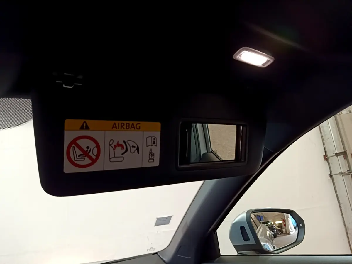 Détail du pare-soleil côté conducteur avec miroir et avertissement airbag, rétroviseur extérieur gris clair d’un Audi Q2 2020.