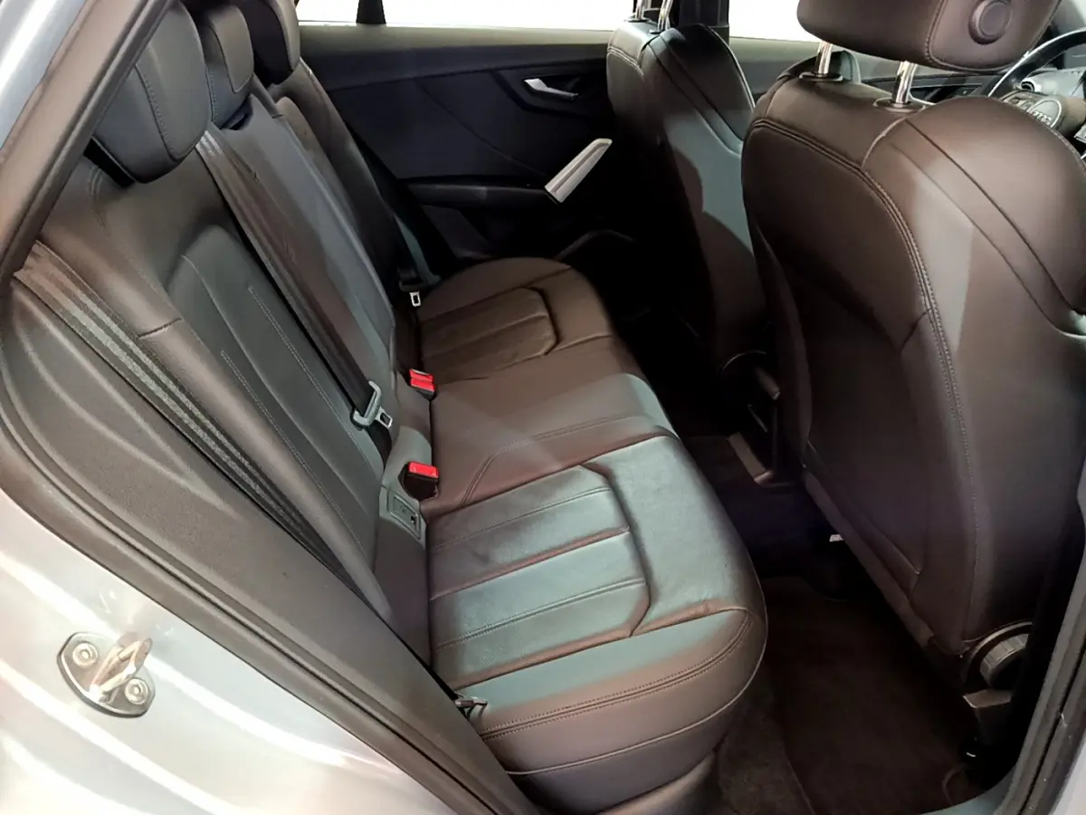 Vue côté gauche sur l’intérieur arrière de l’Audi Q2 35 TDI 150 Design 2020 avec sièges en cuir noir et portière grise ouverte.