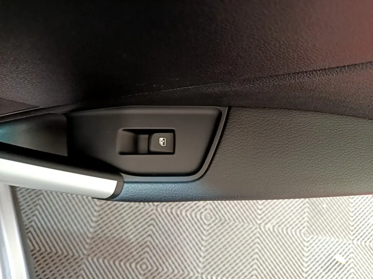 Gros plan sur le bouton de commande de la vitre électrique côté conducteur de l’Audi Q2 gris clair 2020.