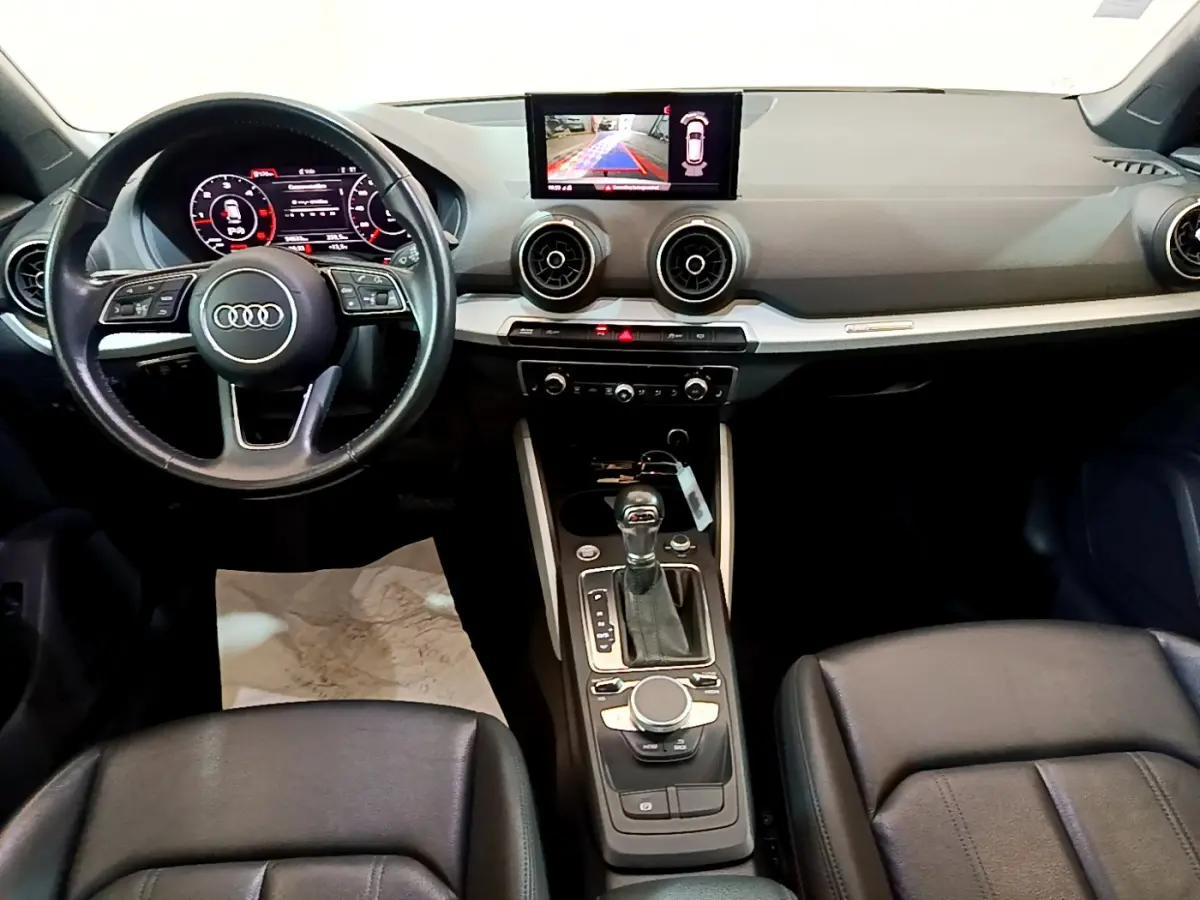 Vue intérieure de l'Audi Q2 35 TDI 150 Design 2020, tableau de bord noir avec écran central et volant cuir multifonctions.