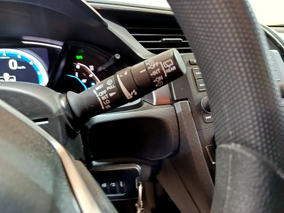 Gros plan sur la manette d’essuie-glace à gauche du volant de la Honda Civic gris foncé 2020, tableau de bord partiellement visible.