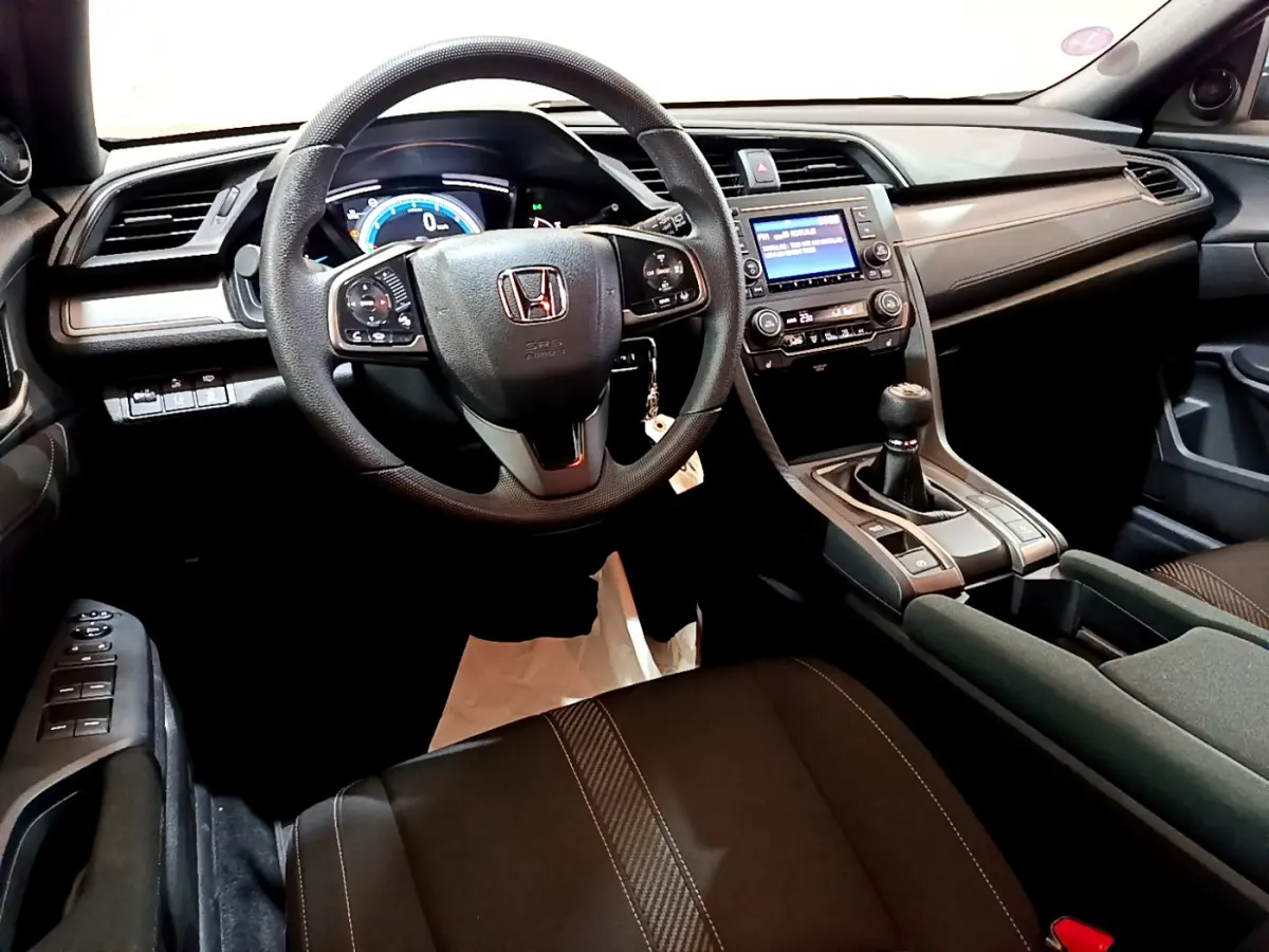 Intérieur noir de la Honda Civic 1.0 i-VTEC 2020, vue du poste de conduite avec volant multifonctions et boîte manuelle.